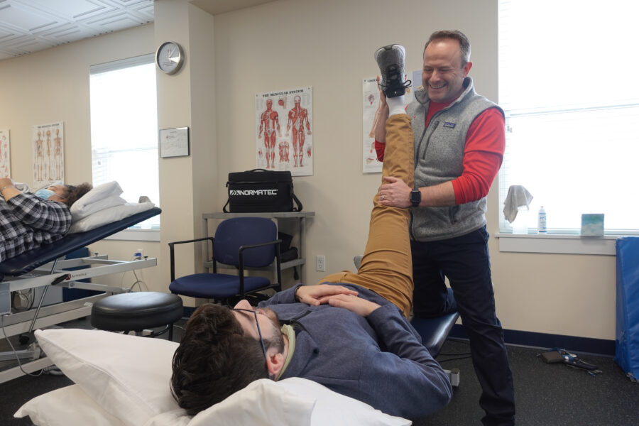 Orange Physical Therapist holding leg of male patient