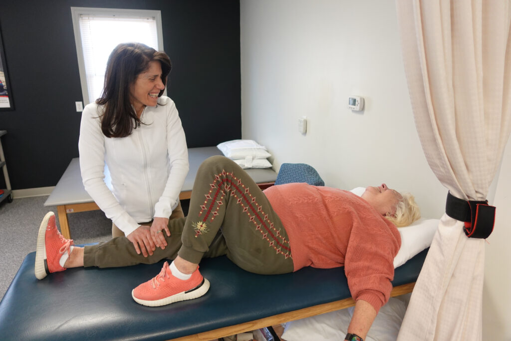 Essex Physical Therapist laughing with patient as she does a leg exercise 
