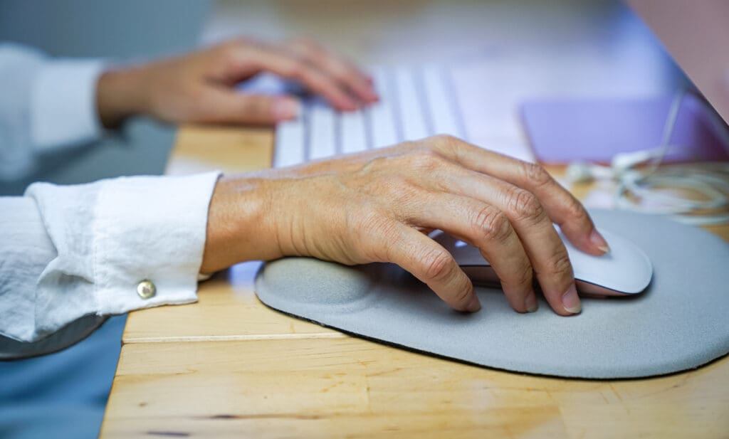 Woman's fingers clicking on mouse, resting her wrist on wrist rest. Ergonomic concept,. Close up view.