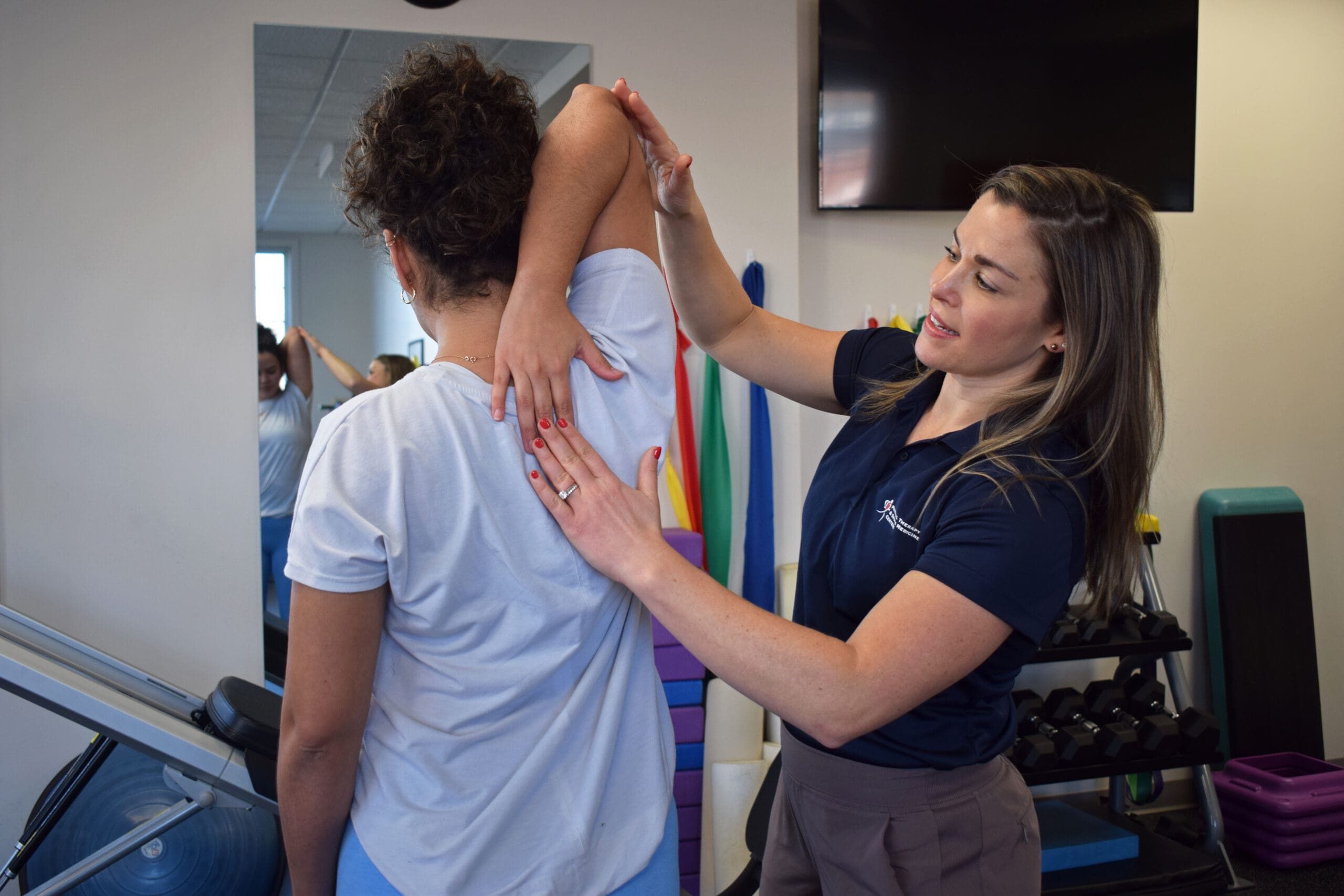 Physical Therapy & Sports Medicine Centers (PTSMC) Wethersfield. Kasey Adinolfi, physical therapist, assessing shoulder flexibility of patient.