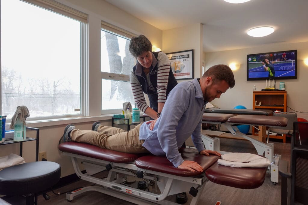 Physical Therapy & Sports Medicine Centers (PTSMC) Waterbury. Female physical therapist treating male patient's low back. Male patient is in cobra pose on a treatment table